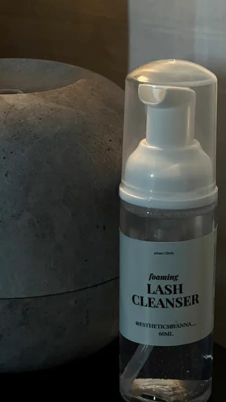 A bottle of Esthetics by Anna foaming lash cleanser beside a concrete diffuser